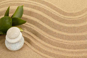 Fototapeta na wymiar balance zen stones in sand and green leaves