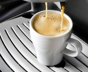 Coffee maker pouring  espresso coffee in  cup