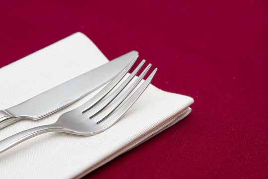 Knife And Fork With White Napkin On Red Tablecloth