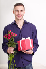 young man holding flowers and gift box