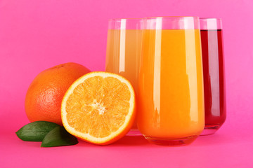 Glasses of juise with leafs and fruits on pink background