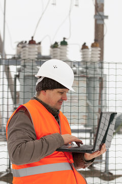 Engineer with computer near the electricity substation
