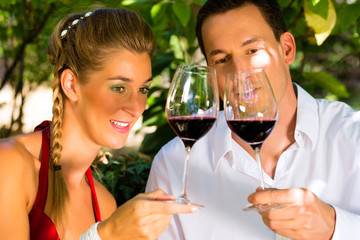 Woman and man in vineyard drinking wine