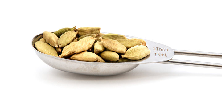 Cardamom pods measured in a metal tablespoon