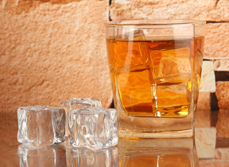 Glass of whiskey and ice on brick wall background