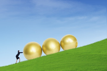 Businesswoman push golden eggs on hill