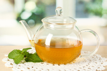 Teapot with mint on table in room