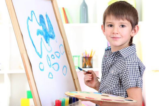 Little boy painting paints picture on easel - Powered by Adobe
