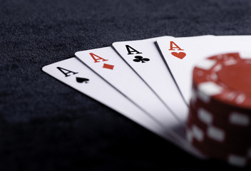 four aces high on black table with chips