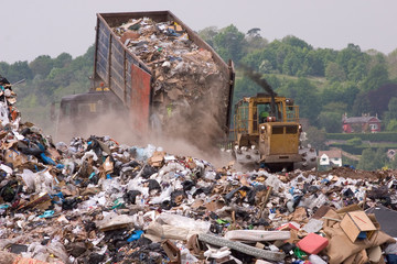A bulldozer and garbage truck on a landfill waste site - obrazy, fototapety, plakaty