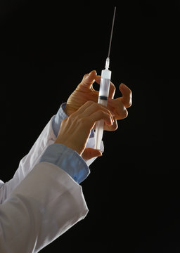 Closeup On Hands Of Medical Doctor Knocking On Syringe