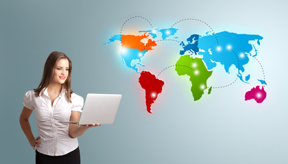 Young woman holding a laptop and presenting colorful world map