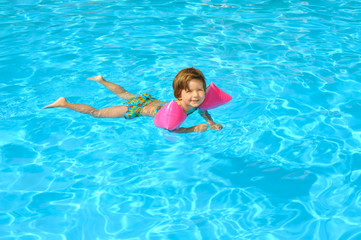 Fototapeta na wymiar Toddler girl learning to swim in the swimming pool