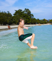 young happy boy with brown hair enjoys  jumping in the beautiful