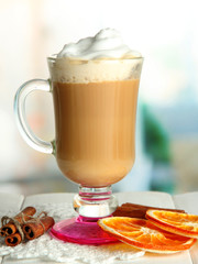Fragrant coffee latte in glass cup with spices, on wooden table