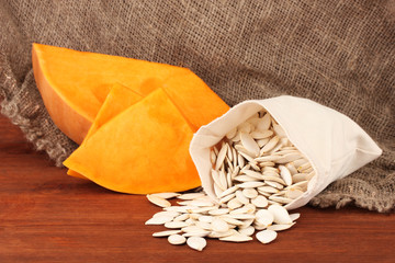 Pumpkin seeds in sack, on wooden background