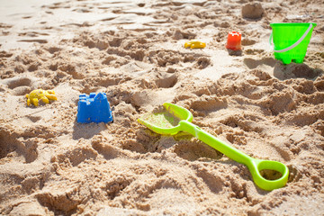 Fototapeta na wymiar Zabawki piasek, zielone wiaderko i łopata r. na plaży