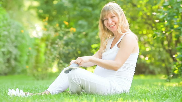 Happy  young pregnant woman playing with bootee in spring park