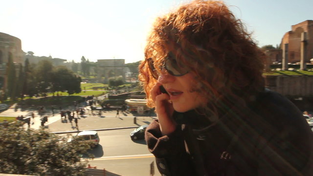Young smiling woman talking on cell phone, against colosseum