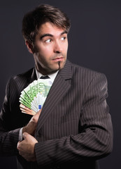 Mann im Anzug steckt Geldscheine ein