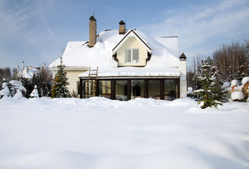 house and its garden under snow and blue sky in winter