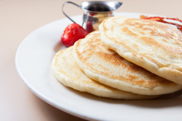 side view of stack of pancakes with bacon and syrup