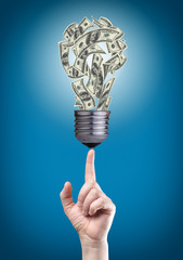Light bulb with money banknotes on tip of finger