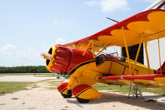 Colorful vintage airplane by a hanger