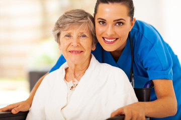 happy senior woman on wheelchair with caregiver - 49000494