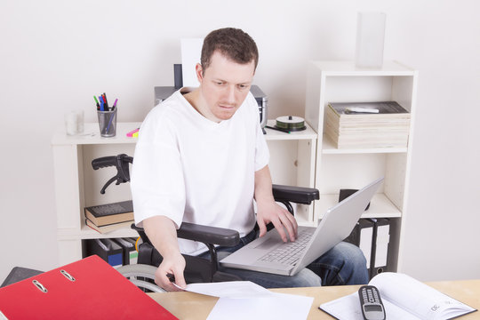 Man in wheelchair with laptop at work