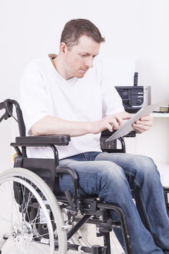 Man in wheelchair with tablet computer at work
