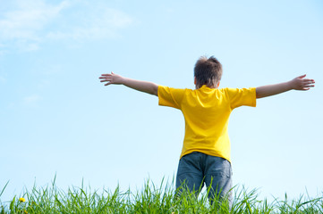 A boy stands on a green grass