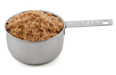 Light brown soft / muscovado sugar presented in a cup measure