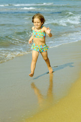 Toddler girl running at beach