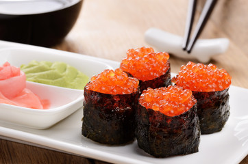 Mixed sushi on a white plate with soy sauce wasabi and ginger