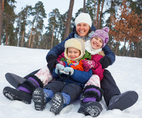 Funny family is sledging in winter-landscape