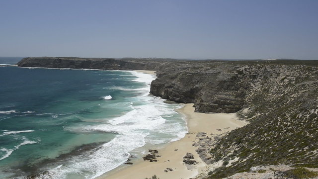 Ocean waves crashing on a sandy beach with cliffs in Australia
