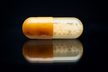 Yellow and White pill (capsule) macro shot, isolated on black
