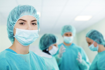 Young female surgeon with medical team in back before surgery