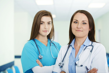 Portrait of young female doctor with intern in background