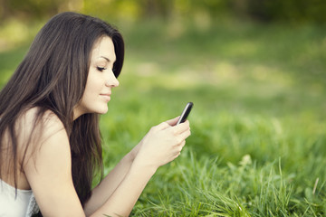 Young woman texting on meadow - obrazy, fototapety, plakaty