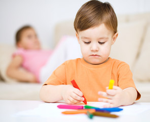Little boy is drawing on white paper