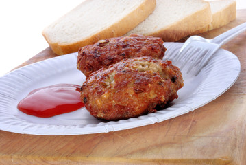 zwei Frikadellen mit Ketchup auf einem weißen Pappteller