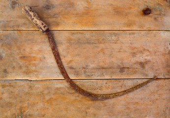 Antique sickle hand tool rusted on aged vintage wood