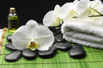 Beautiful white orchid with pebbles and towel on green mat