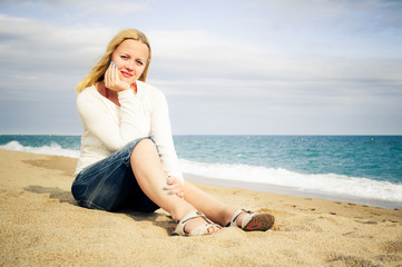 Fototapeta na wymiar kobieta siedzieć na plaży nad morzem w dżinsach