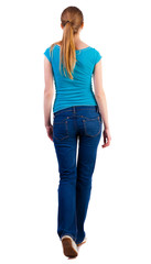 Obraz premium back view of walking woman in jeans and shirt.