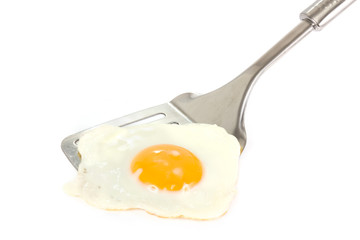 Fried egg on a silver spatula over white