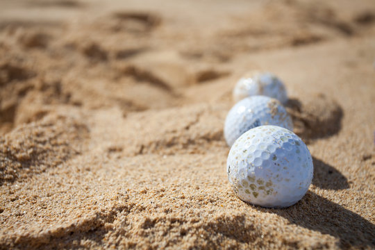 Three golf balls in a sand trap