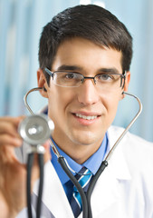 Happy doctor with stethoscope, at office